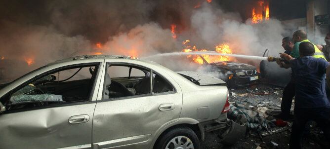 Miembros de Protección Civil extinguen el fuego en el lugar de la explosión