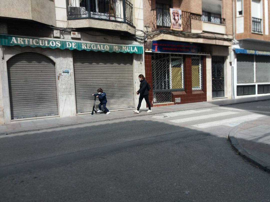 Un niño pasea con su madre, por la calle General Fresneda