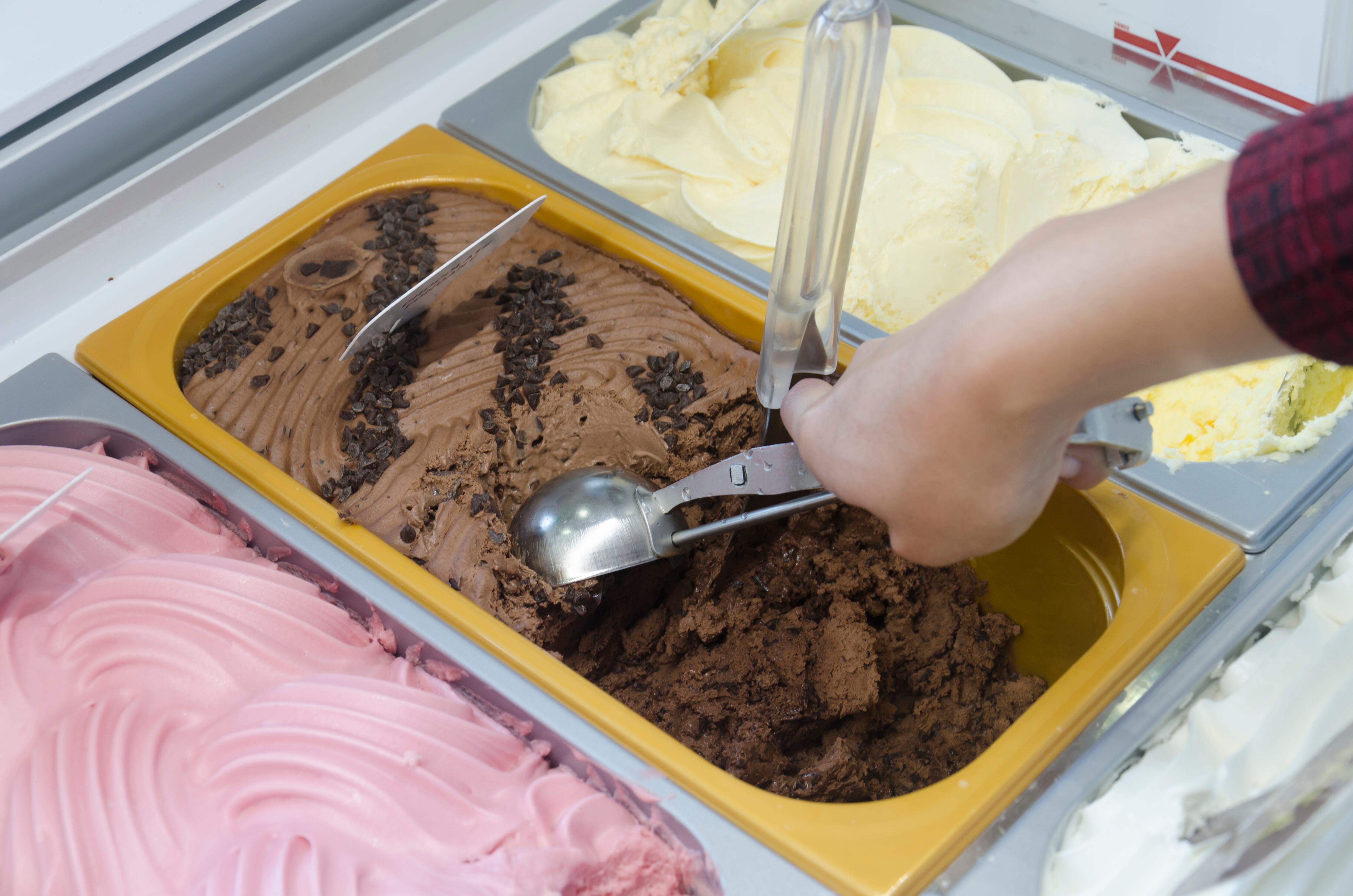 Una mujer coge una bola de helado de chocolate.