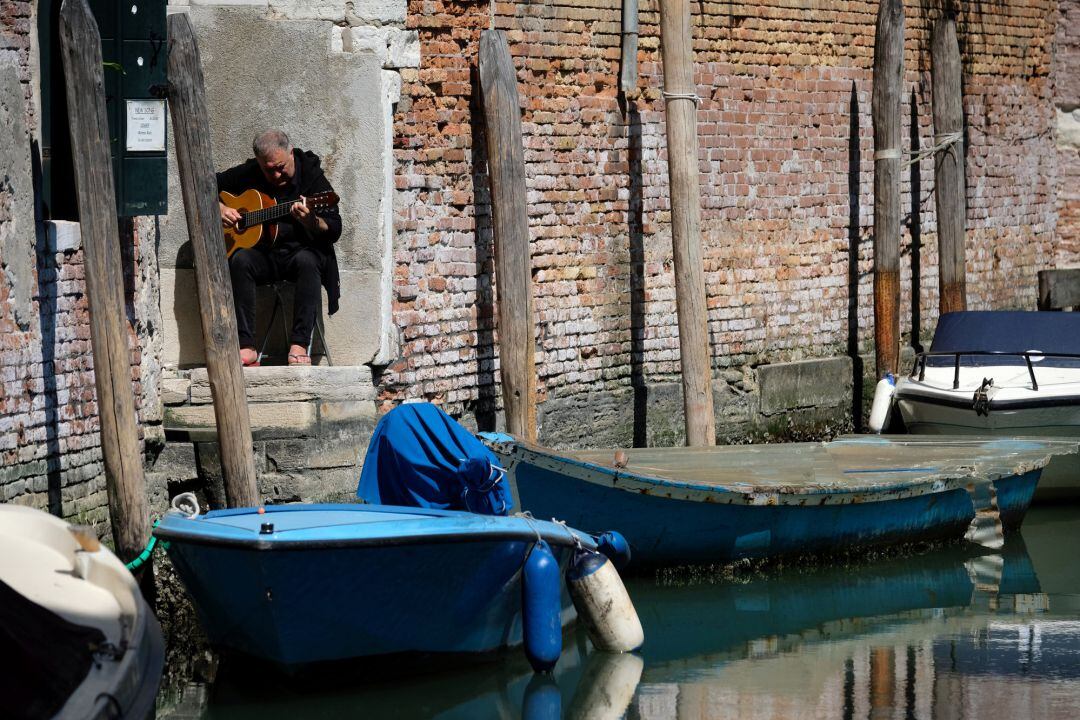 Un hombre toca la guitarra en la puerta de su hogar en Venecia