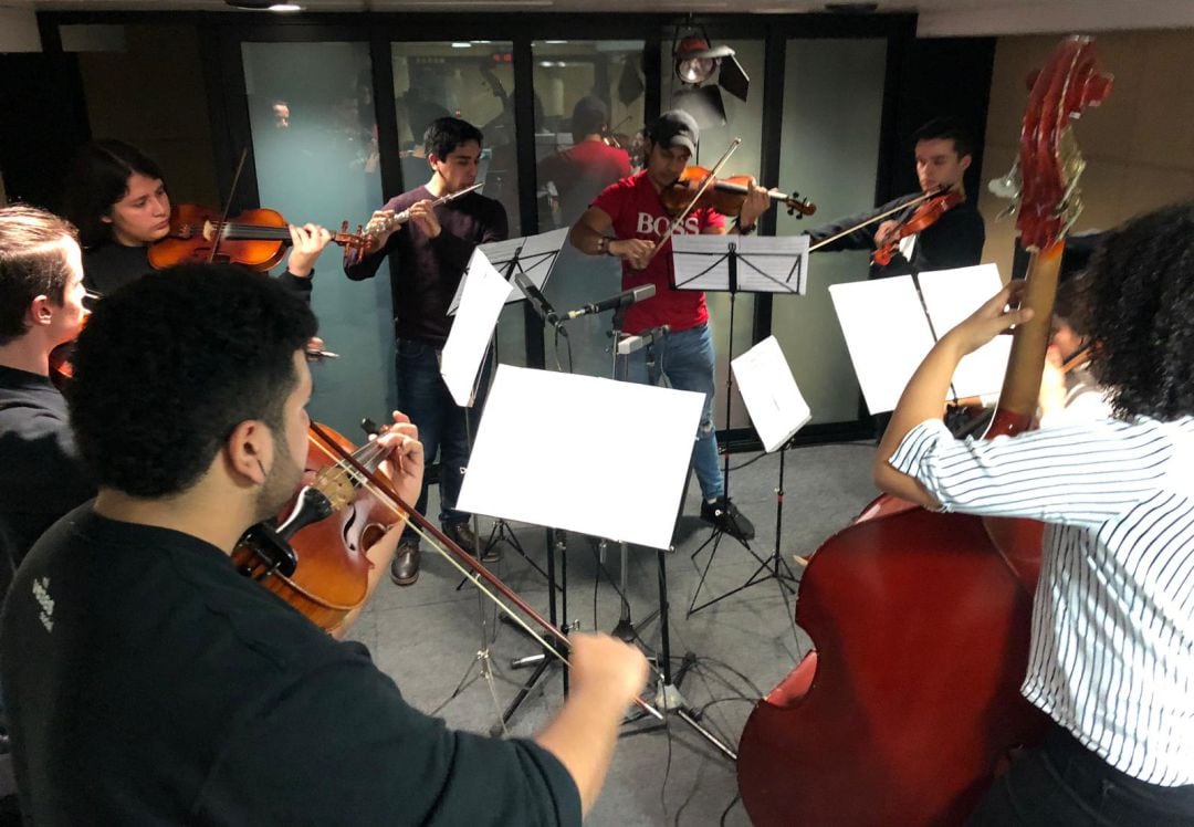 Ocho integrantes de la orquesta Vozes interpretan una pieza en directo en Radio Barcelona