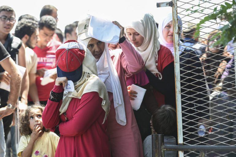 Mujeres y niños esperan su turno para conseguir un permiso que les permita cruzar Macedonia
