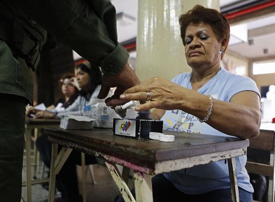 Un funcionario electoral  mancha el dedo de un soldado con tinta, después de haber votado en Venezuela.