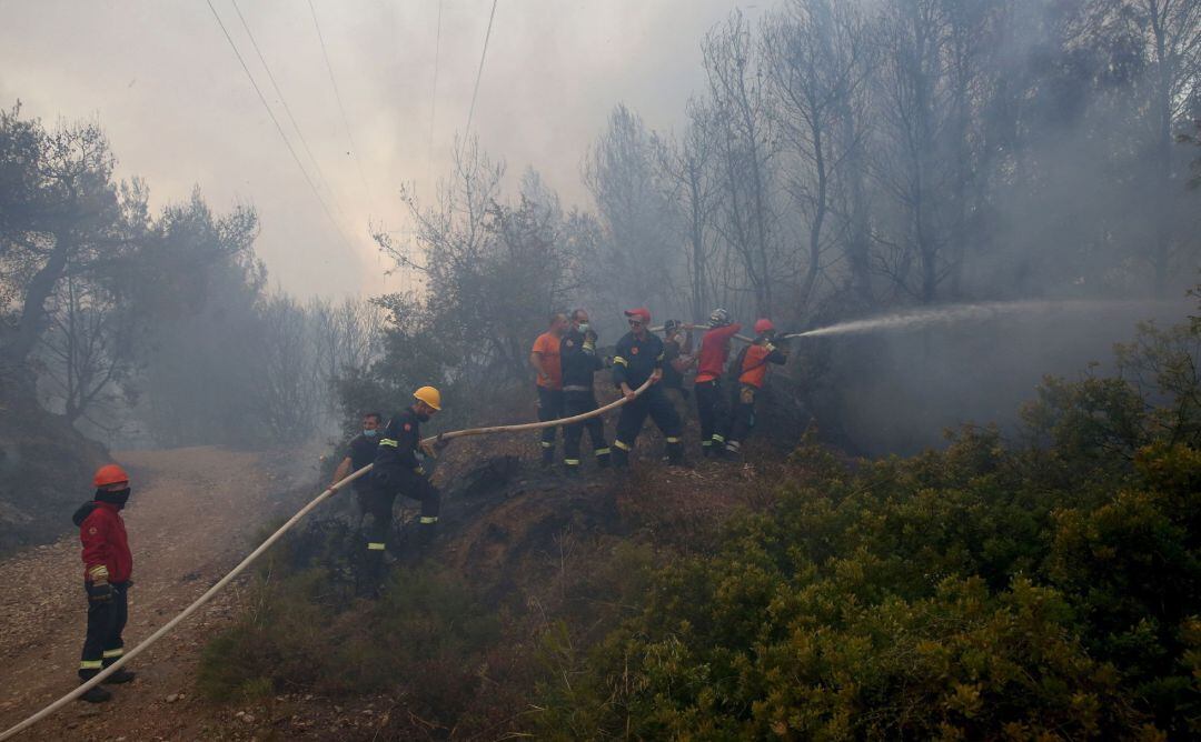 Los bomberos griegos tratan de extinguir el fuego en un paraje a las afueras de Atenas.