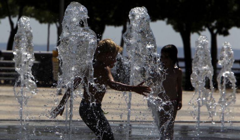 Uno niños se refrescan en una fuente