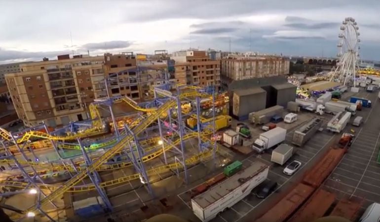 Imagen aérea de la feria de atracciones que se instala en el Grao con los edificios de viviendas al fondo