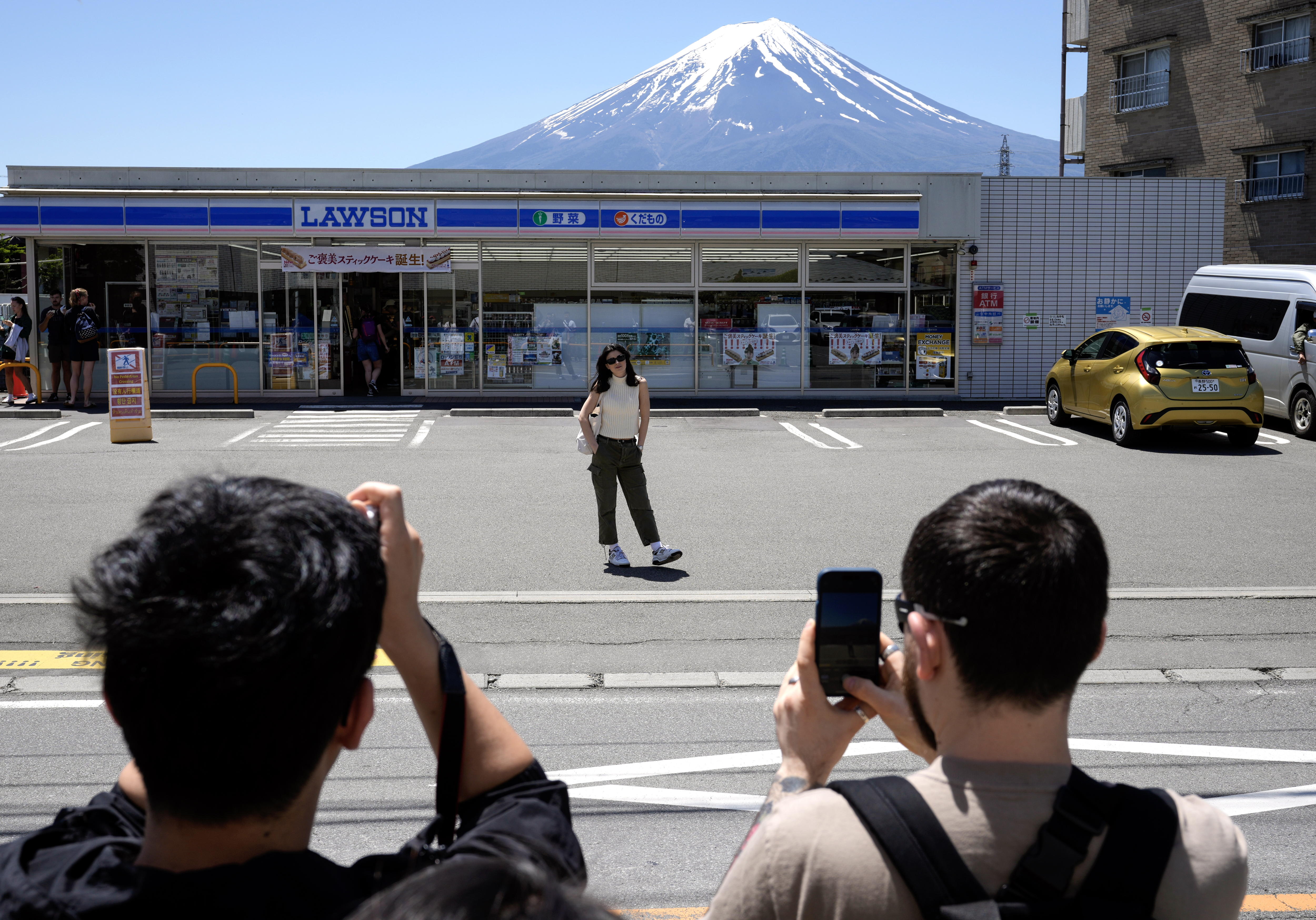 Una turista posa frente a la tienda Lawson Kawaguchiko Ekimae para retratarse con el monte Fuji de fondo.