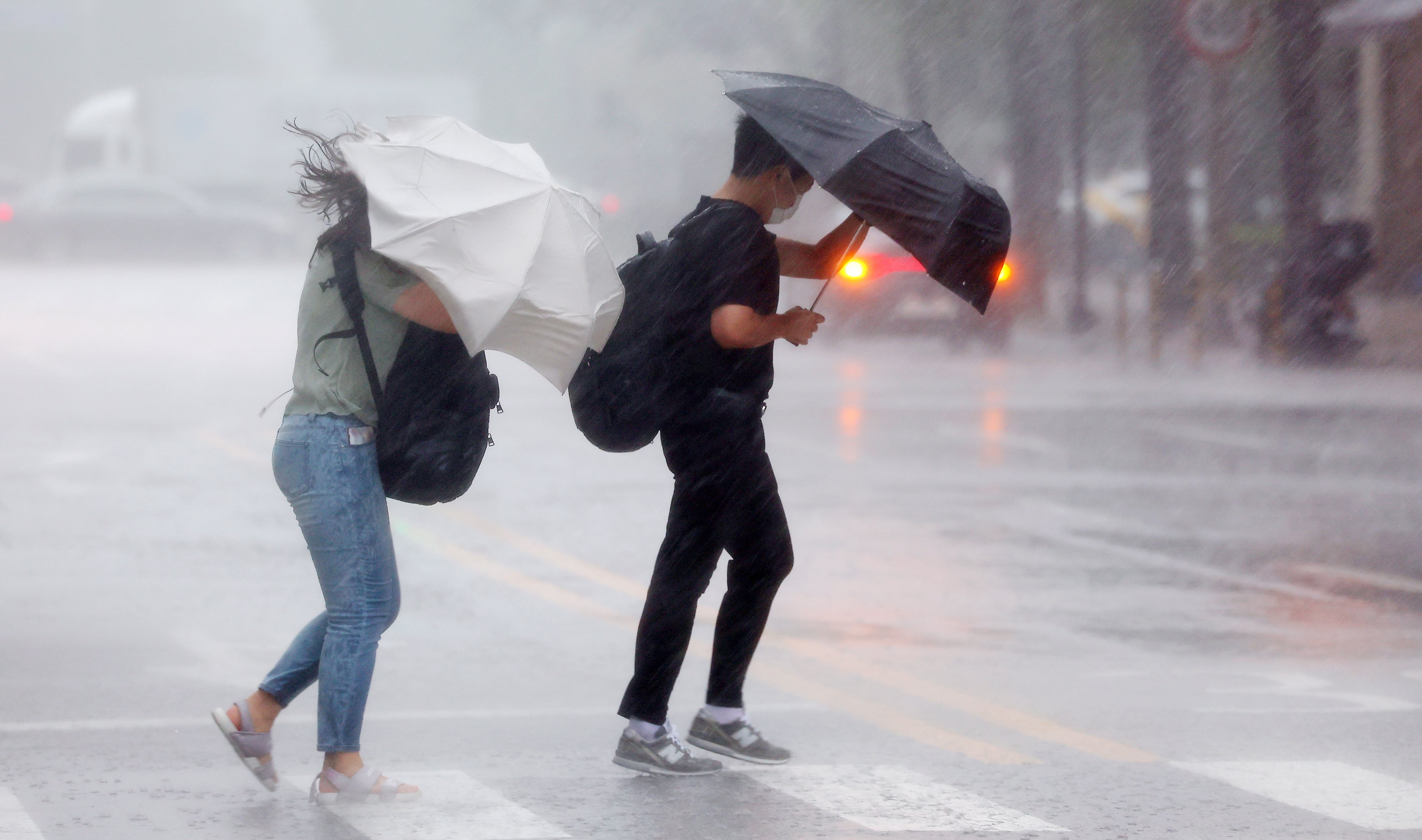 Imagen de archivo de Dos personas intentando protegerse de la fuerte lluvia