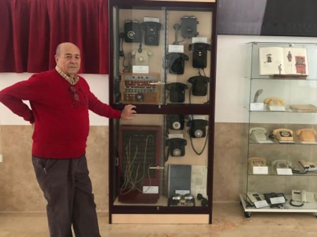 Paco Page junto a las vitrinas de su colección de teléfonos.