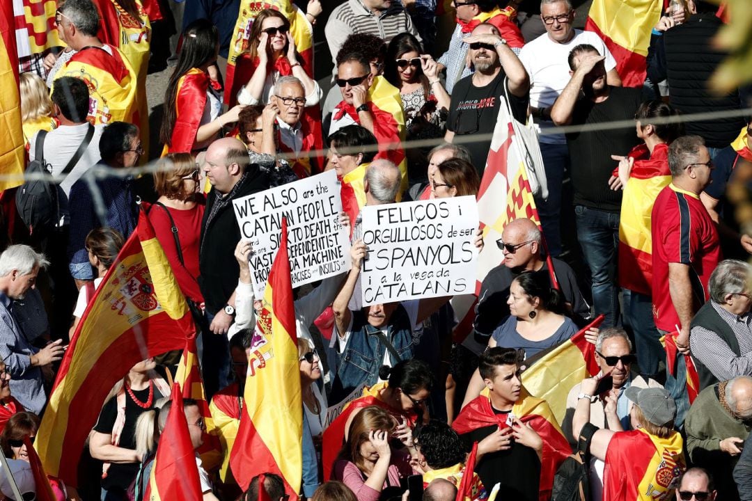 Varias personas esperan el comienzo de la manifestación en la que miles de personas se concentran en el centro de Barcelona, convocadas por Societat Civil Catalana, para decir &quot;basta&quot; al proceso independentista.