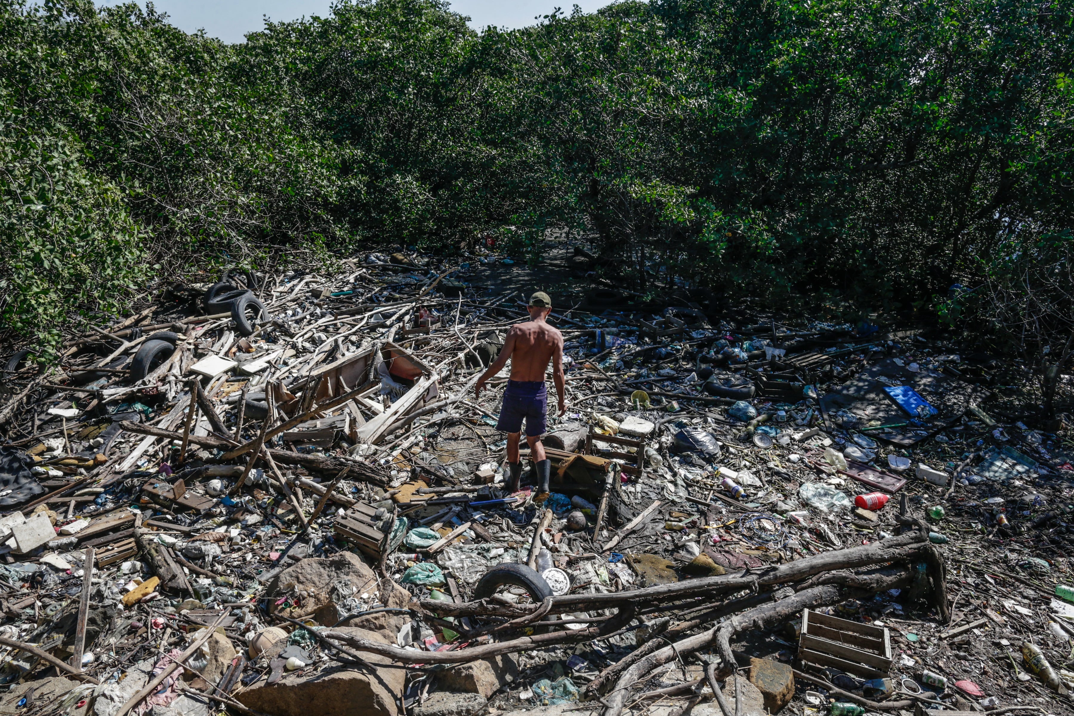 Fotografía de archivo fechada el 2 de junio de 2021 que muestra a un hombre que recicla material en una playa de la bahía de Guanabara, en Río de Janeiro (Brasil)