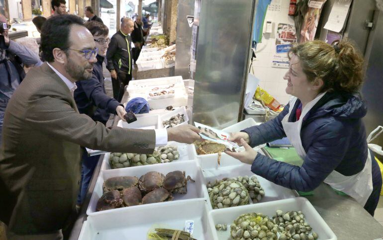 El portavoz del PSOE en el Congreso, Antonio Hernando, reparte propaganda electoral del candidato socialista, durante la visita al mercado de abastos, esta mañana en Santiago de Compostela