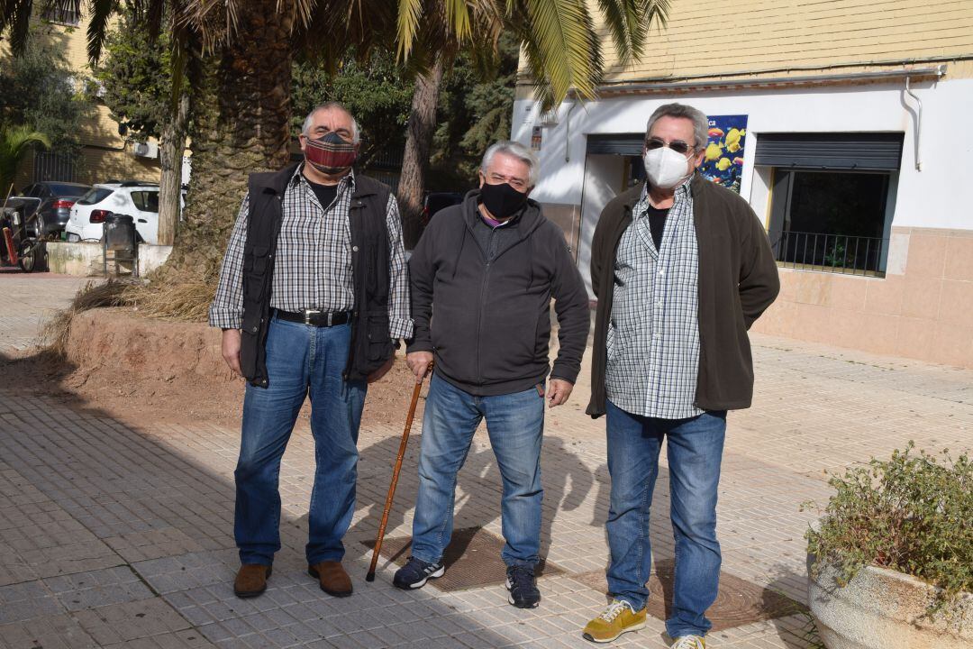 Representantes vecinales posan delante de una palmera en claro estado de abandono y mantenimiento.