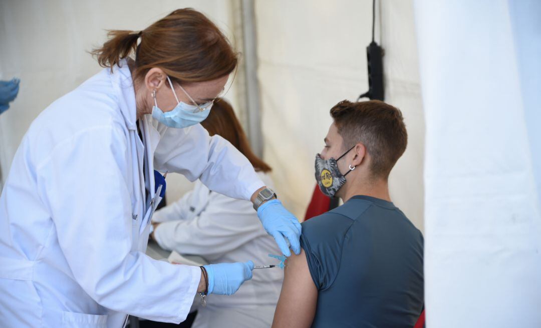Una enfermera vacuna a un joven frente al coronavirus.