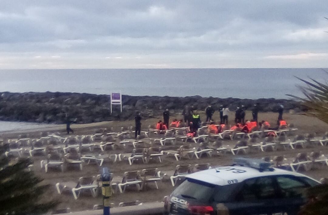 Momento en el que la Policía nacional atiende e identifica a los migrantes que llegaron hasta la playa de Las Vistas, en la localidad de Los Cristianos