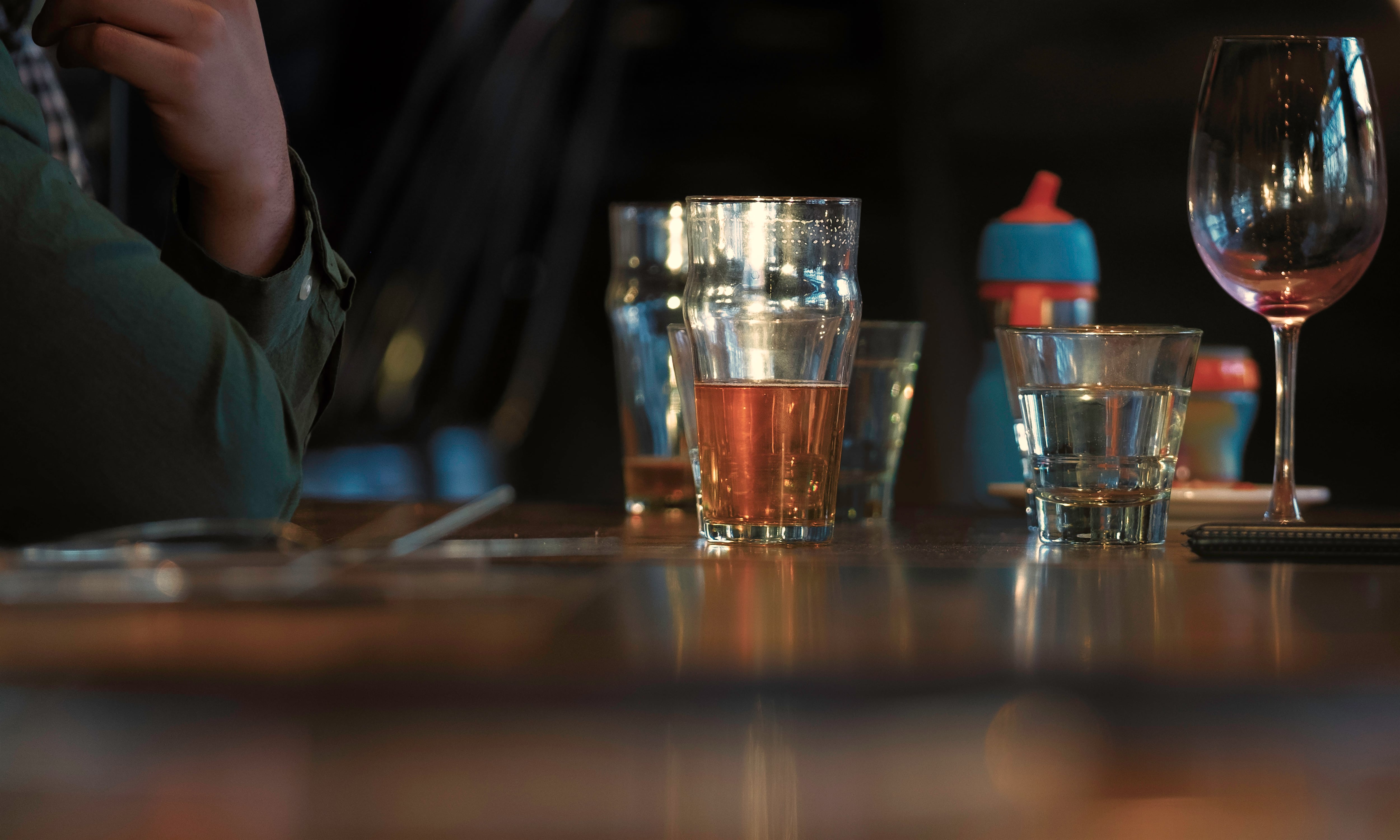 Glasses of beer and baby water bottle on the table in the restaurant dark wooden background