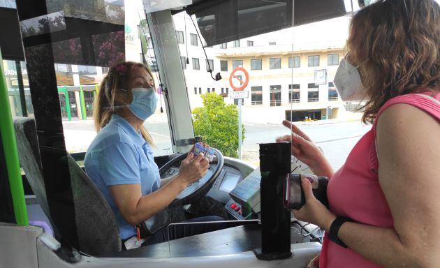 Toñi Moreno atiende a una usuaria a su entrada al autobús junto a la estación del AVE
