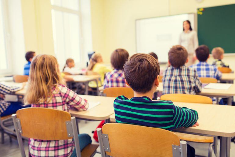 Niños en un aula escuchan a su maestra.