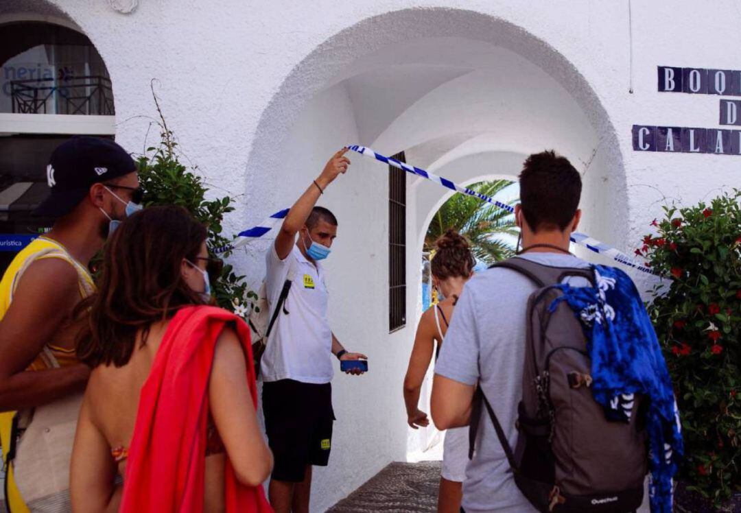 Un auxiliar de playa de la Junta de Andalucía (i), permite el acceso a bañistas a la playa de Papagayo en Nerja (Málaga)