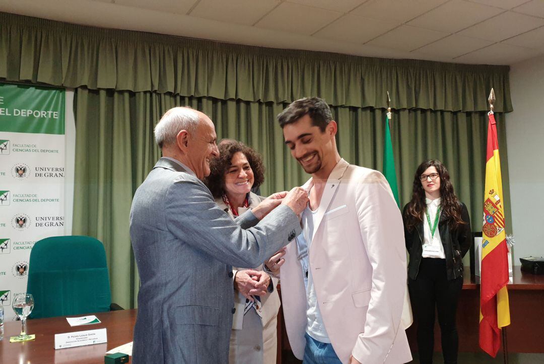 El patinador Javier Fernández recibe la insignia de oro de la Facultad del Deporte de la Universidad de Granada a manos del decano y ante la rectora