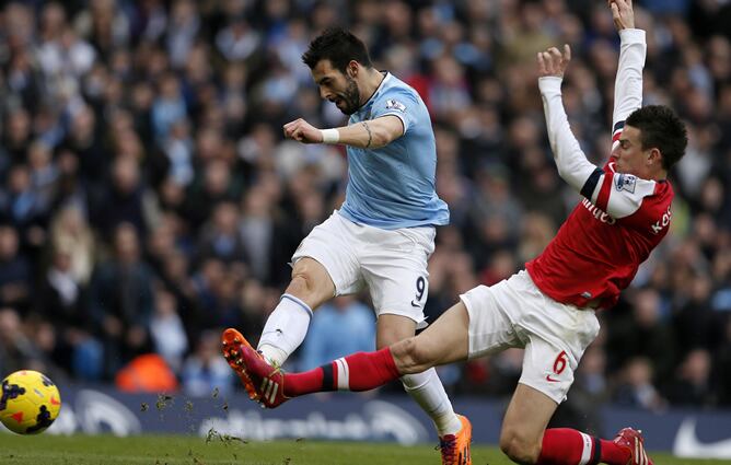 El delantero vallecano chuta ante la presión del central francés del Arsenal