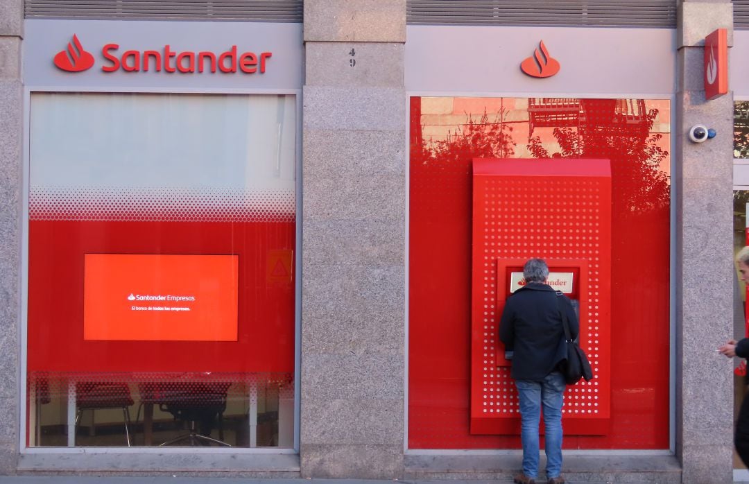 Una persona saca dinero de un cajero del Banco Santander.