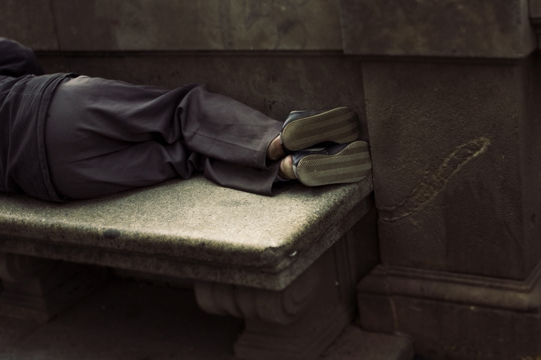 Un hombre durmiendo sobre un banco.