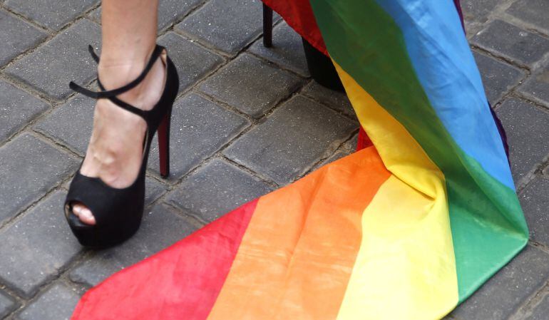 Una persona envuelta en la bandera del colectivo homosexual asiste hoy a la carrera de tacones, en la madrileña calle Pelayo, una de las actividades de la Fiesta del Orgullo Gay en Madrid, la más grande de Europa, que se celebra hasta el 3 de julio en la 