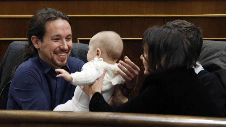 El líder de Podemos, Pablo Iglesias, coge a la hija de la diputada Carolina Bescansa, en el hemiciclo del Congreso donde hoy se celebra la constitución de las nuevas Cortes Generales 