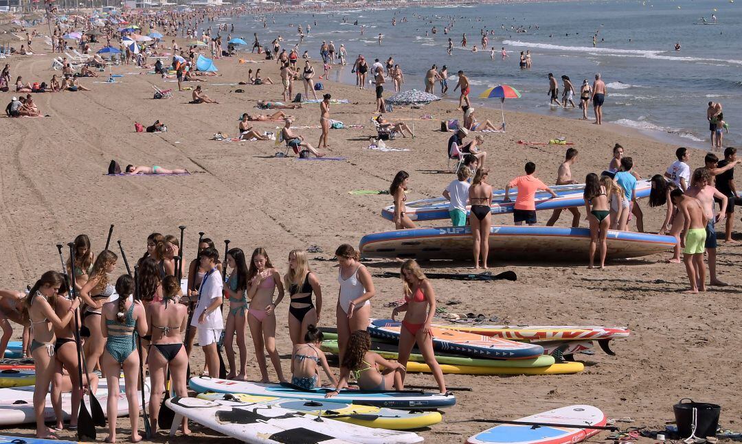 Varios jóvenes tomando el sol y haciendo deporte en una playa de Alicante. 