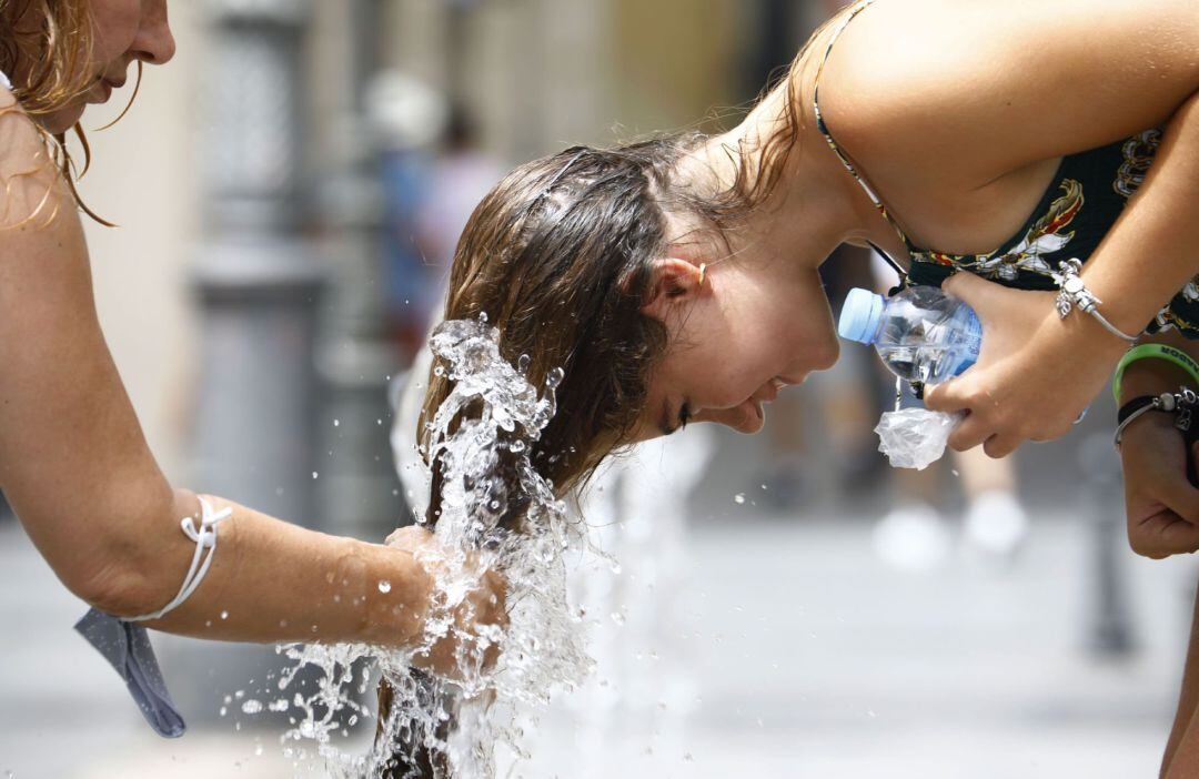 Una mujer se refresca en una fuente del centro de Córdoba.