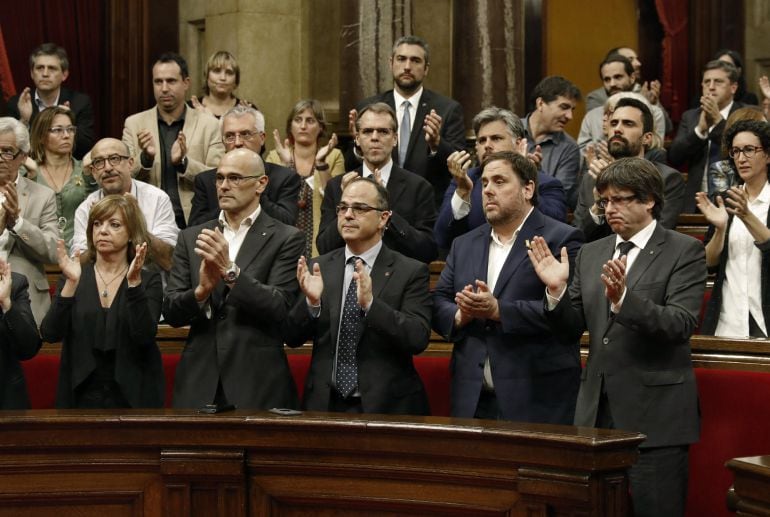 El presidente de la Generalitat de Cataluña, Carles Puigdemont (d), el vicepresidente del Govern, Oriol Junqueras (2d) y el resto del govern y diputadosde Junts pel Sí, aplauden para homenejear a Jordi Cuixart y Jordi Sanchez