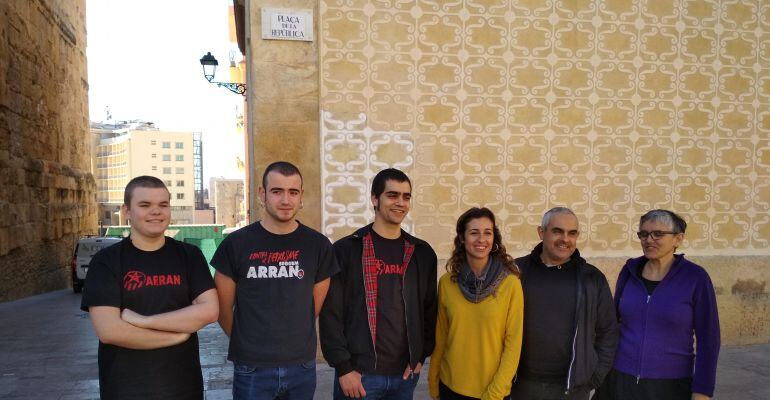 Mebres de la CUP i Arran davant d'un dels cartells canviats.