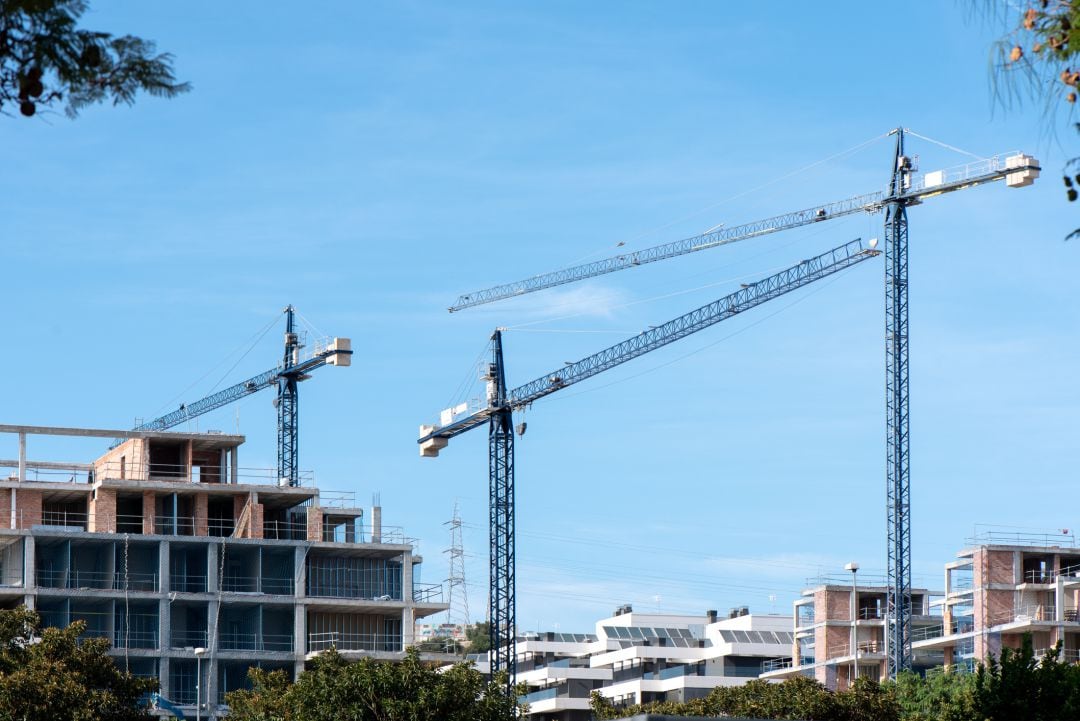 Varias grúas entre edificios en obras.