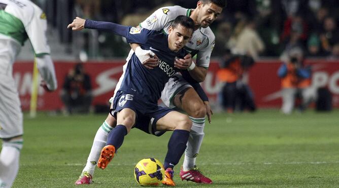 El defensa del Elche Botía (detrás) agarra a Camacho, del Málaga, durante el partido de Liga en Primera División