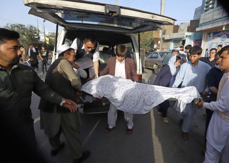 Varias personas cargan en un coche el cuerpo sin vida de un hombre tras un atentado suicida en Kabul.