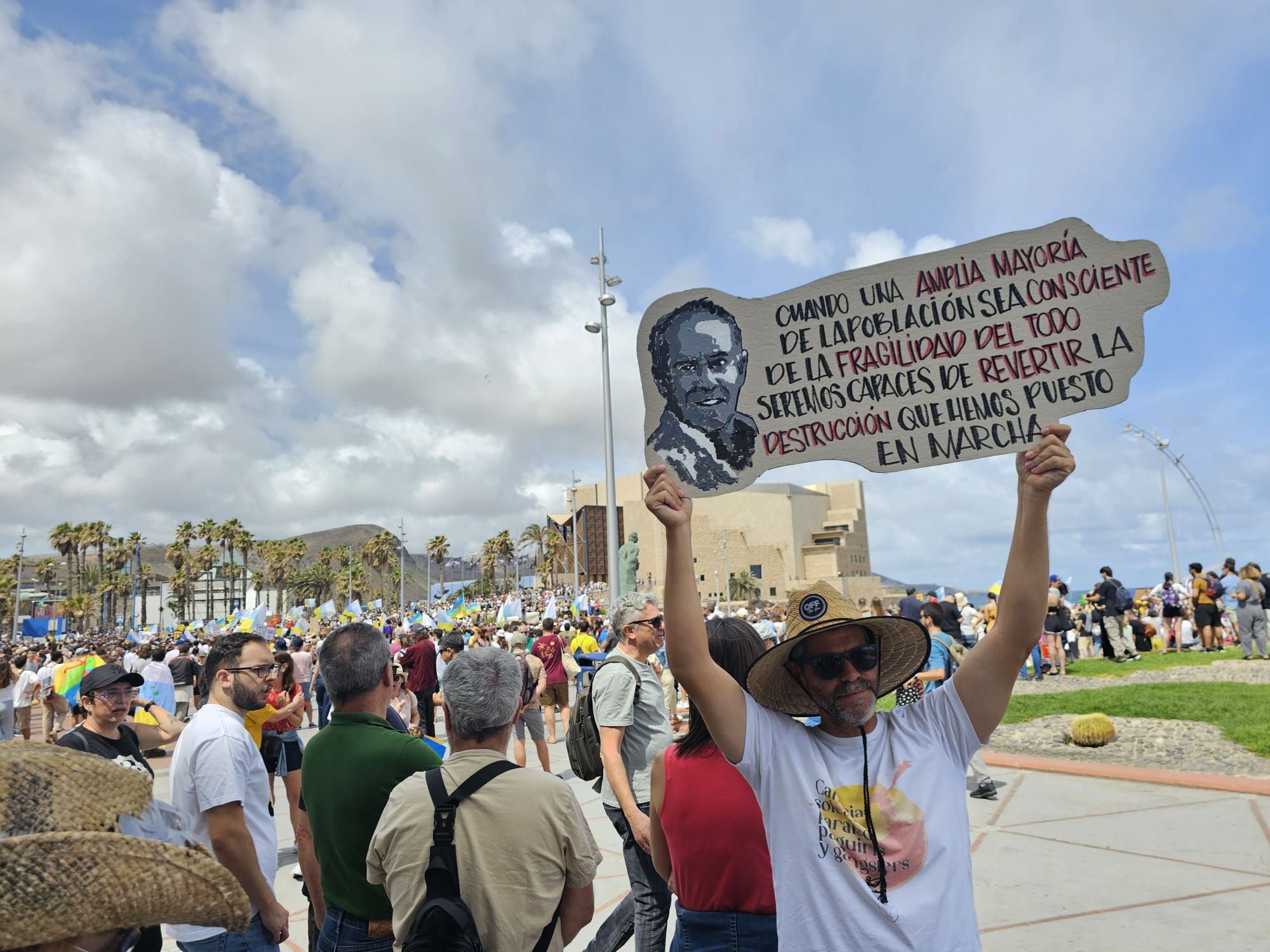 Uno de los manifestantes con la pancarta de Manrique en Las Canteras el 20A
