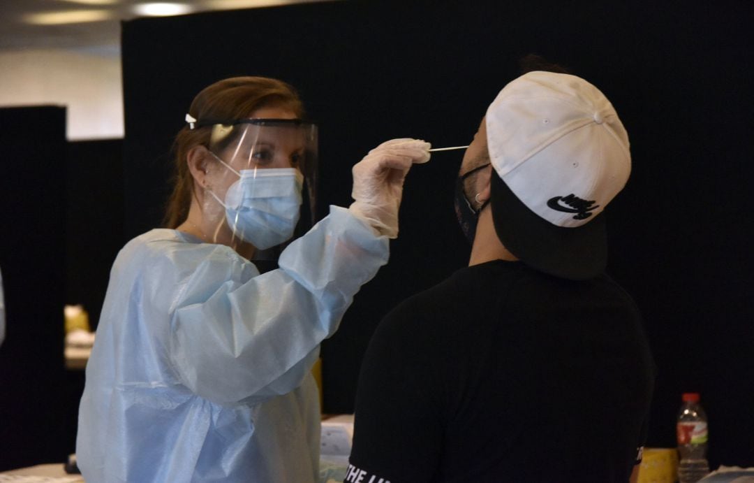 Una trabajadora sanitaria realiza un test de antígenos a un joven.