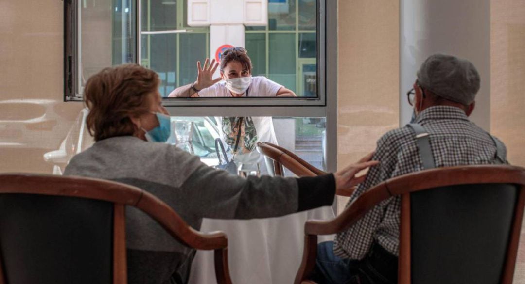 Una persona conversa con sus padres a través de una ventana habilitada en la residencia de mayores