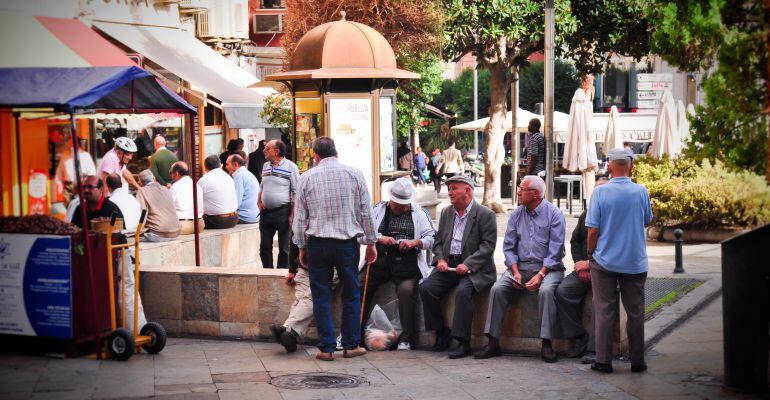 Personas mayores sentadas en la Plaza de la Constitución.