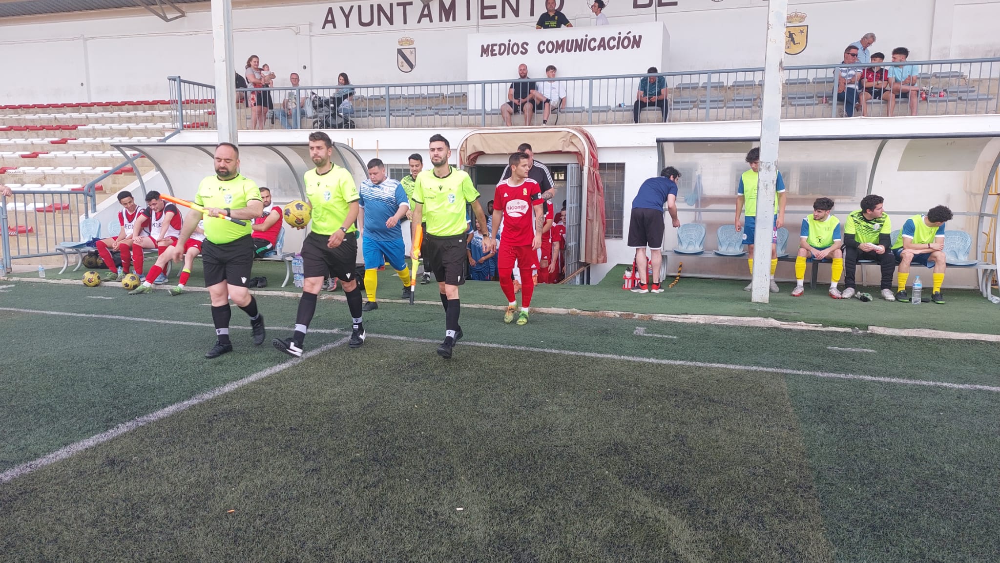 Trío arbitral y los dos equipos saltan al terreno de juego desde el tunal de vestuarios