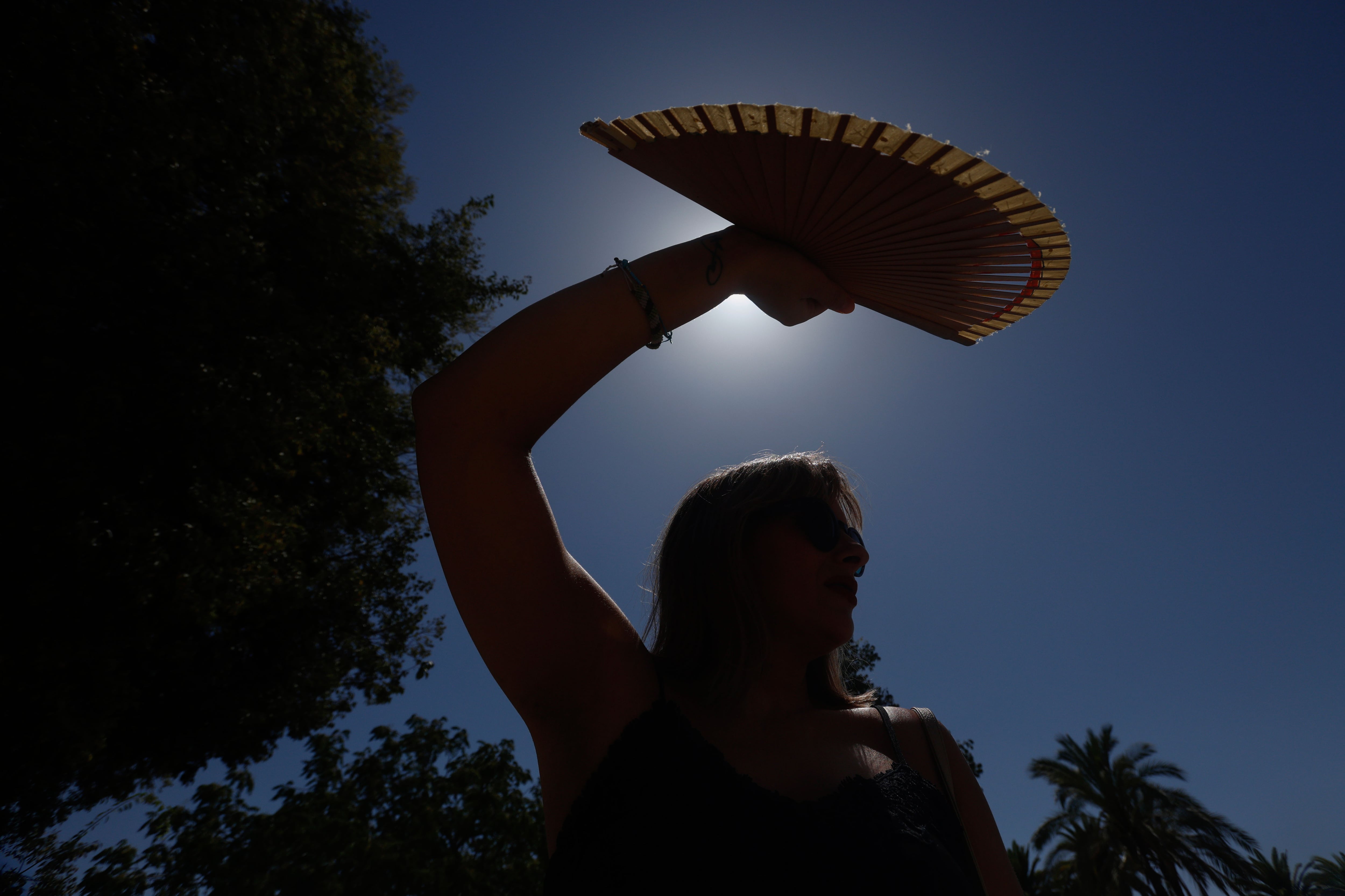 Una mujer se protege con un abanico del sol este lunes, en Córdoba (Andalucía). EFE/ Salas