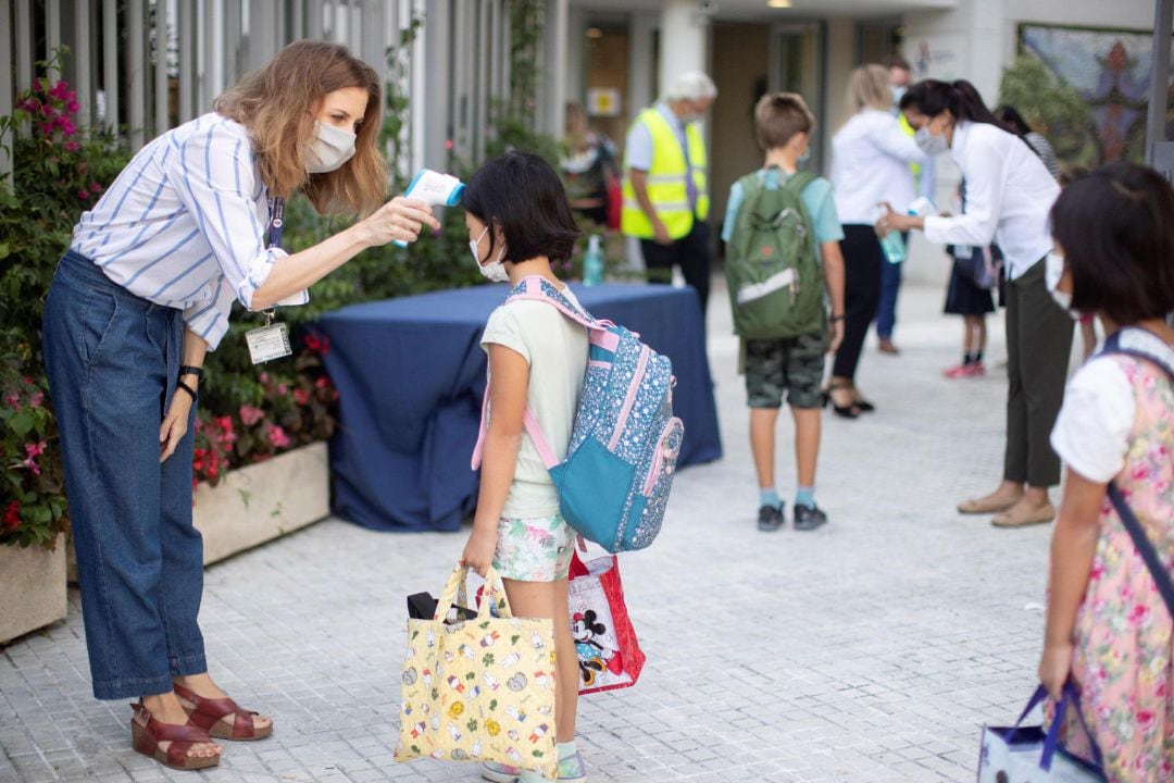 Una trabajadora toma la temperatura a una niña a la entrada de un colegio