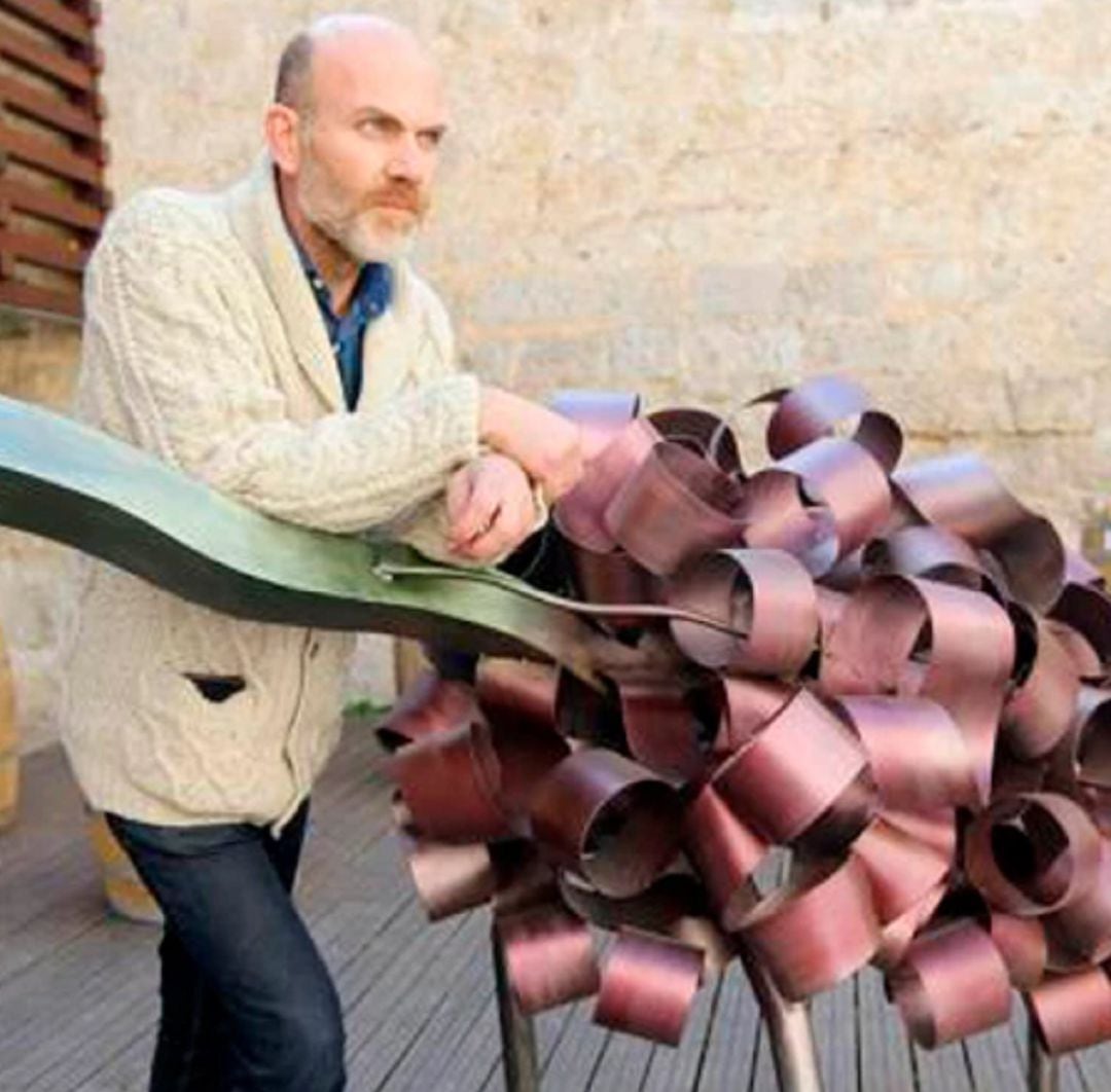 El artista, Julio Galán, junto con su escultura del Museo del Vino