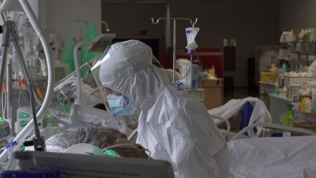 Una sanitaria atendiendo a un paciente en la UCI Covid.