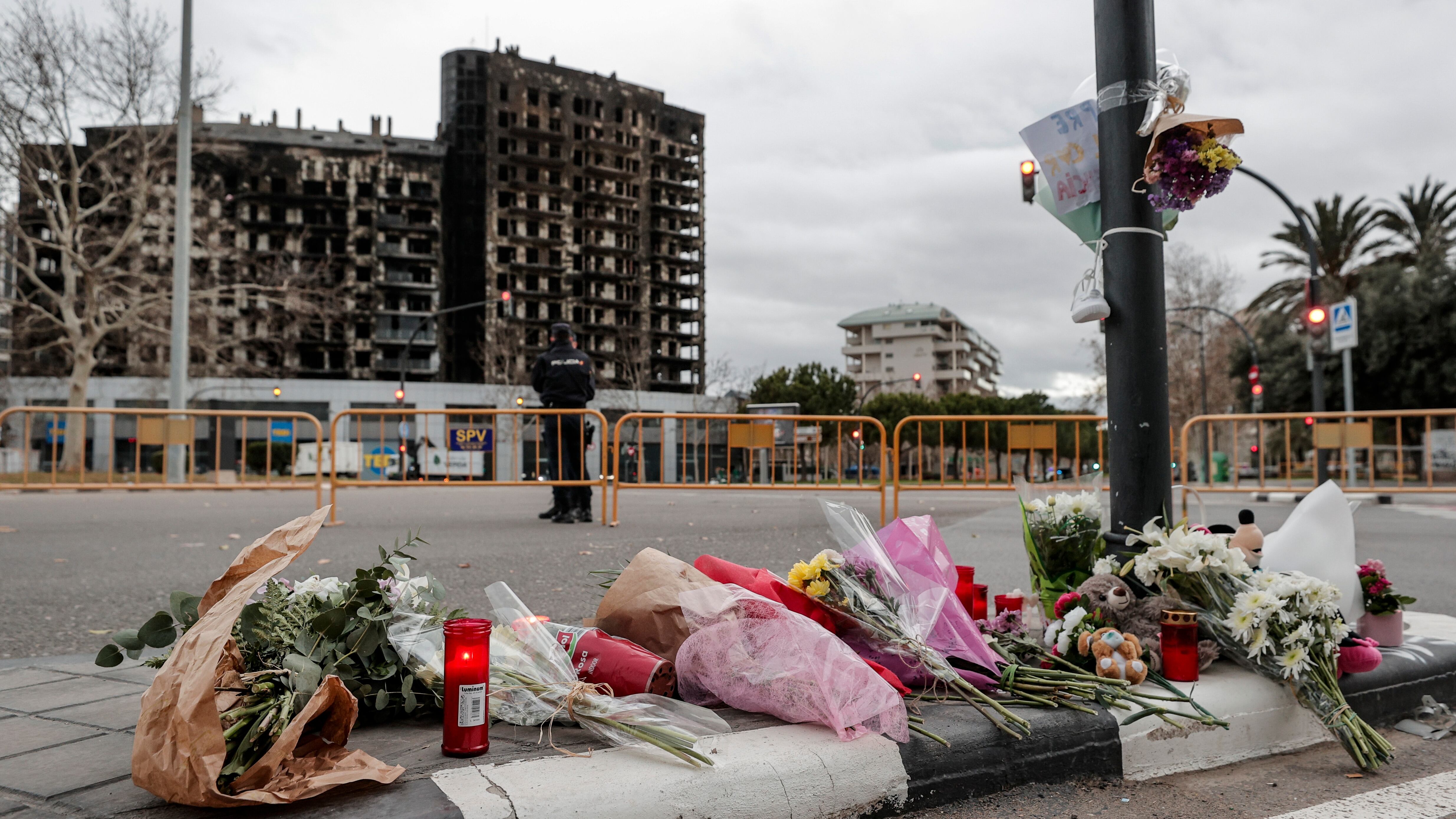 GRAFCVA8671. VALENCIA, 25/02/2024.- Tercera jornada de luto en València por las diez víctimas mortales del incendio de un edificio del barrio de Campanar, donde los bomberos continúan trabajando, mientras siguen adelante la investigación, bajo secreto de sumario, las gestiones para realojar a los vecinos que han perdido sus casas y la atención psicológica a los afectados. En la imagen flores, velas y algún peluche depositados ante el edificio incendiado. EFE/Manuel Bruque
