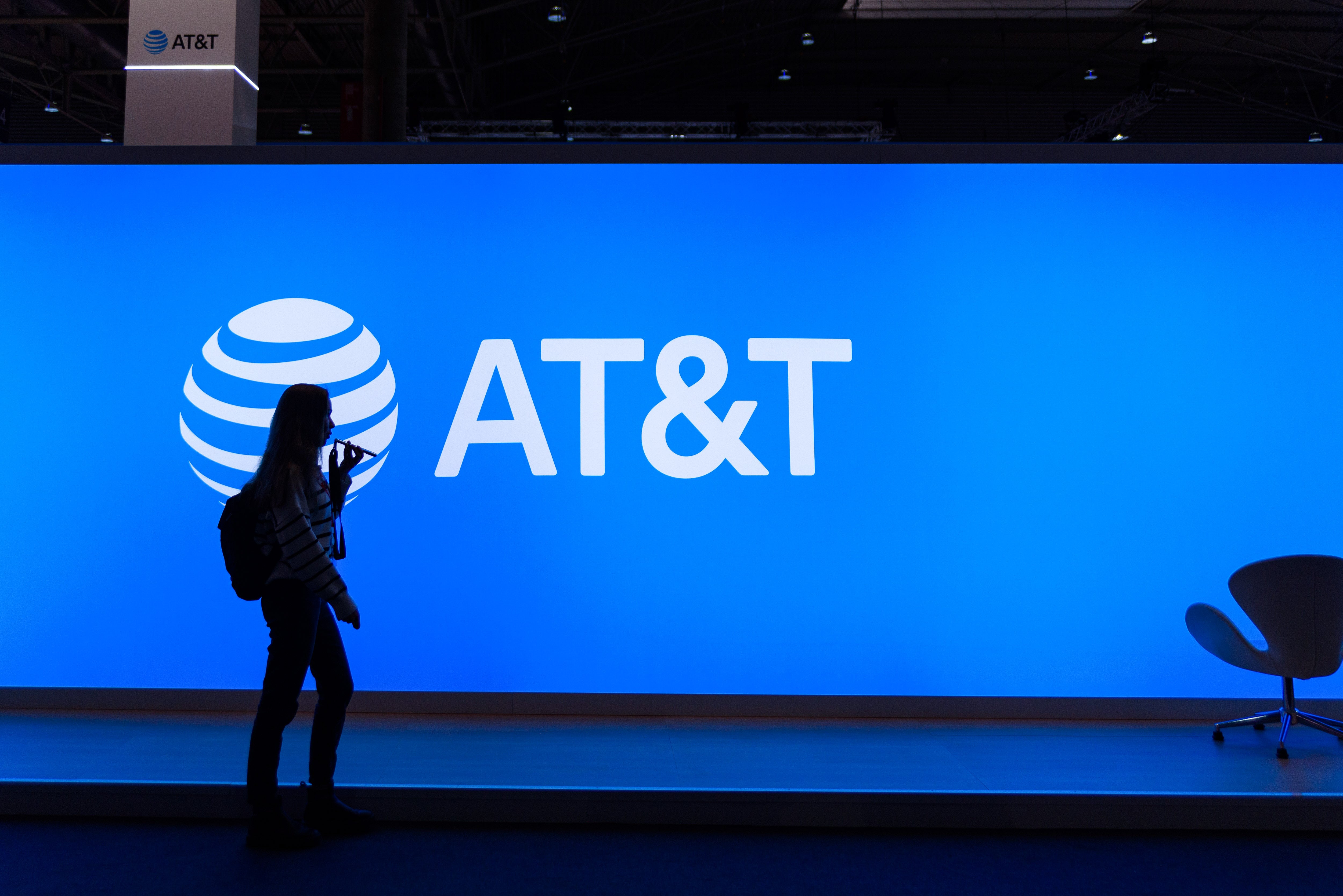 Una mujer paseando delante del logo de AT&T en el Mobile World Congress de Barcelona