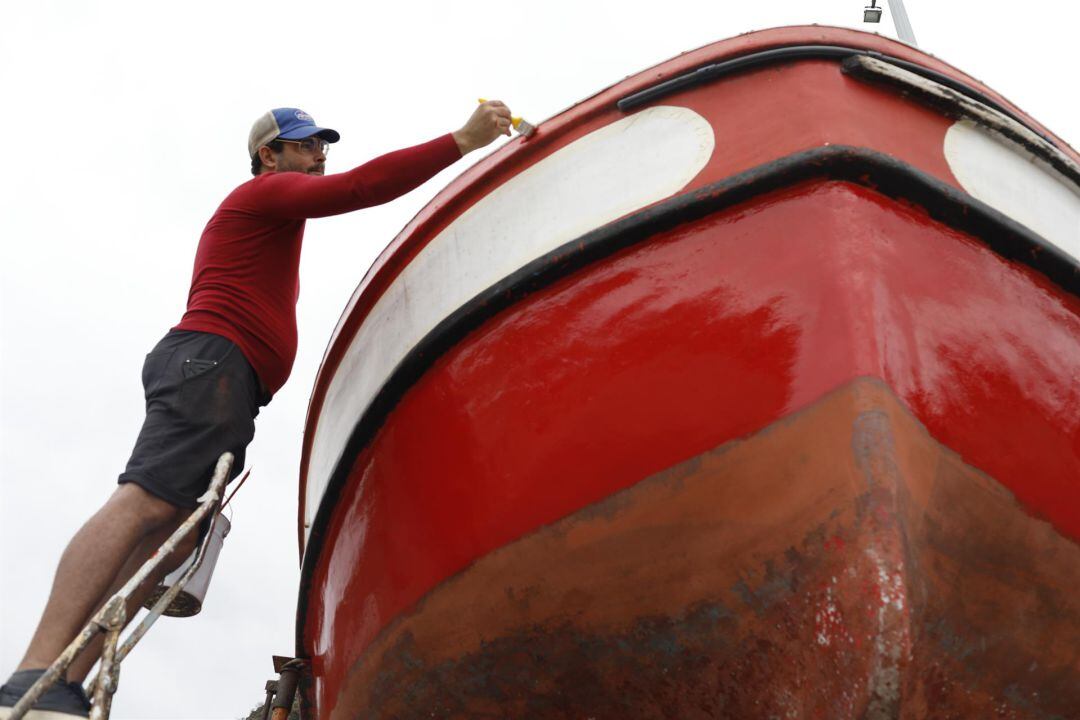 Un pescador pinta una barca en el puerto de Tazacorte