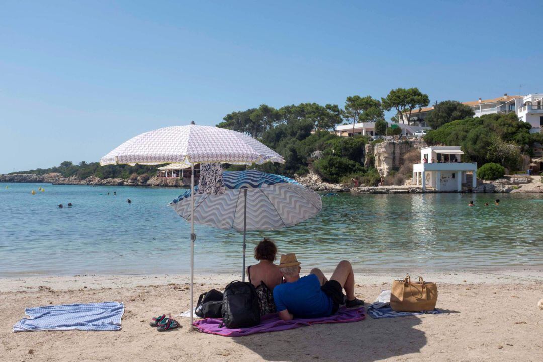 Una pareja toma el sol en la Cala Santandría de Menorca