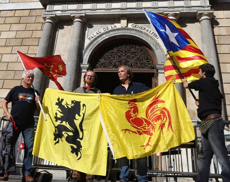  Cuatro personas sostienen las banderas (de izda a dcha) de las regiones de Occitania, Flandes, Valonia y la estelada, ante el Palau de la Generalitat, en el primer día laborable tras la puesta en marcha del artículo 155 de la Constitución para hacer fren